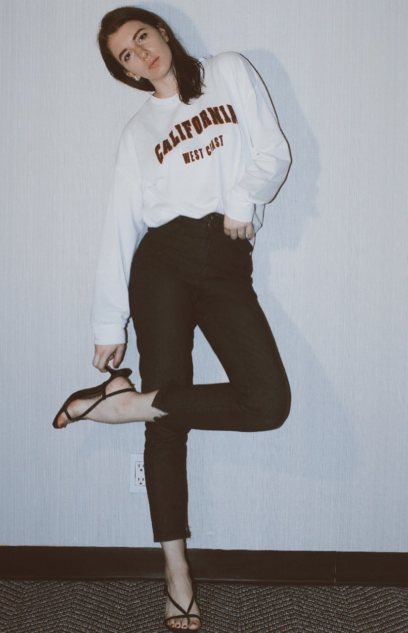 gabrielle arruda wearing slim black jeans with white sweatshirt and strappy heels 