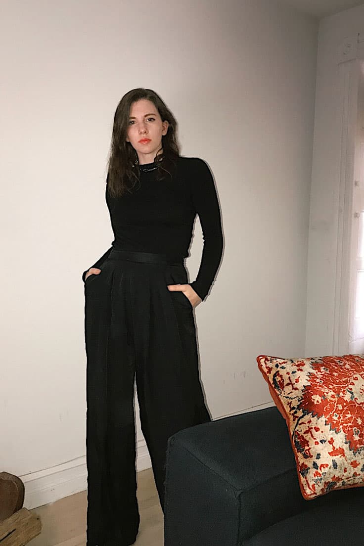 fashion style: minimalist.  style blogger gabrielle arruda wearing monochromatic black outfit. black cashmere sweater with wide leg trouser and simple silver necklace 