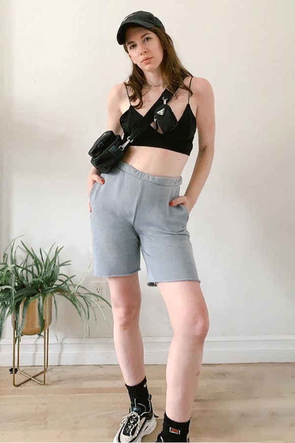 sweatshorts trend outfit idea with baseball cap, sneakers and tube socks, a bralette top and prada bag