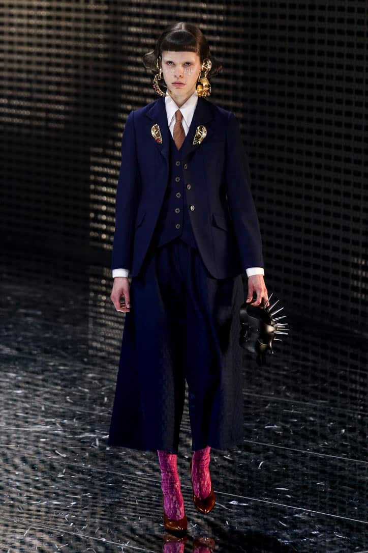 fall fashion trends 2020 gucci runway model wearing equestrian style suit. with pink boots and tie