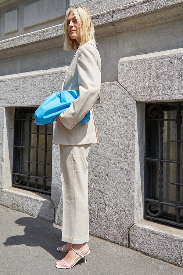 fashion rules to break 2020, you can wear white after labor day. PFW streetstyle image of all white suit and blue pouch bag