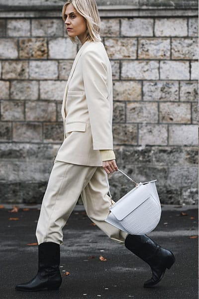STYLE influencer wearing white suit with trousers tucked into boots with designer bag - improve style by using rental fashion services 