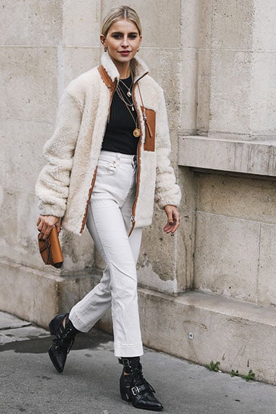 style influencer wearing a easy pair of jeans and t-shirt with interesting sherpa jacket. how to improve your style- use your go-to pieces as a safety net and add a new trend 