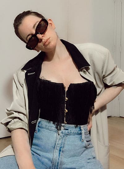 spring fashion trends 2021 on style blogger gabrielle arruda, wearing a fringed corset with baggy jeans and padded shoulder jacket with rectangular glasses. corset spring fashion trend 