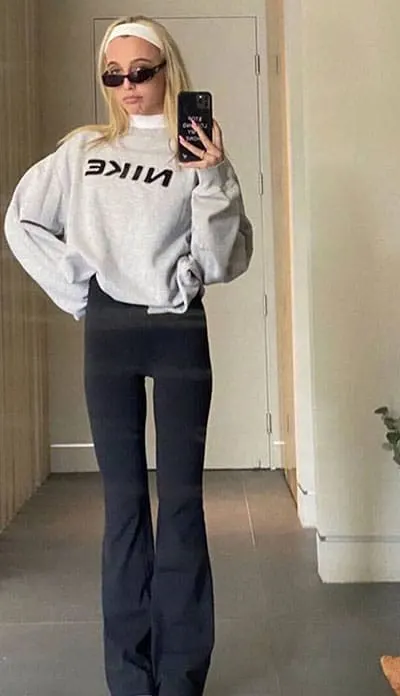 black flare leggings on emma chamberlain with sweatshirt layered over a turtleneck with an elastic headband