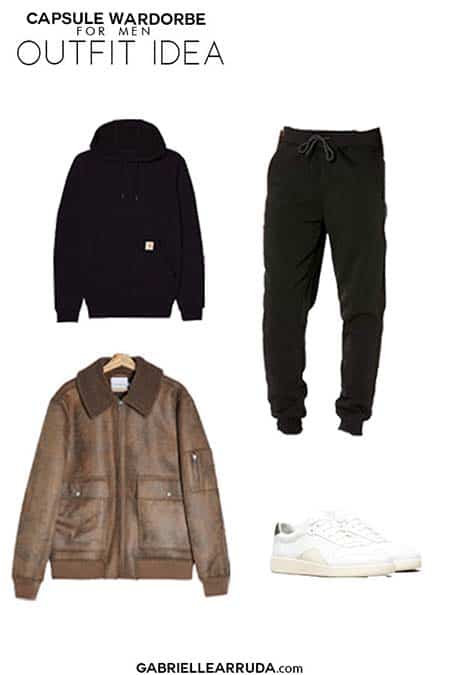 men's capsule wardrobe outfit idea with black joggers, black hoodie, brown leather bomber, and classic white sneakers