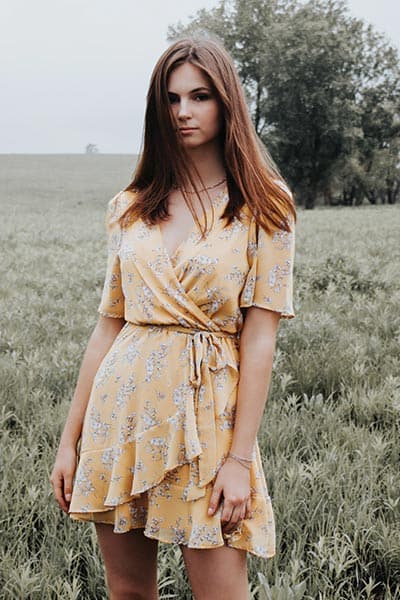 girl next door fashion style, sweet look- cute girl wearing short wrap dress with yellow floral print and ruffle along skirt