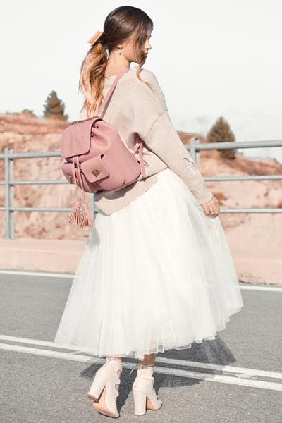girly fashion style, girl in pastel pink outfit, tulle skirt, pink backpack, pastel sweater and bow in hair