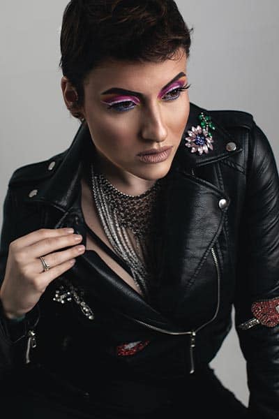 goth fashion style, girl with long chain mail neckalce and leather jacket. elaborate eye makeup 