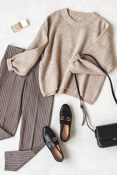 timeless style outfit flatlay- tan sweater with trousers, loafers, black crossbody,