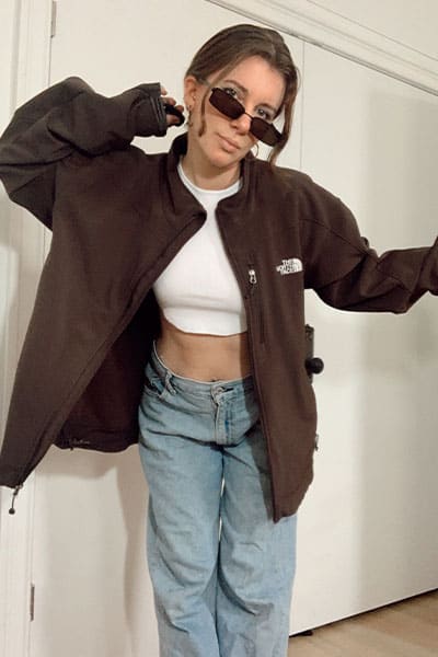 spring fashion trend windbreakers. gabrielle arruda wearing a brown northface windbreaker with white tank and baggy low rise jeans and matrix sunglasses