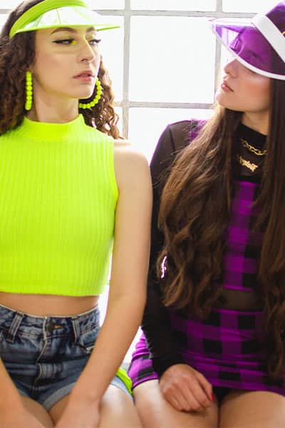 two girls wearing neon and purple tops and accessories, fashion mistake: wearing too much color/print