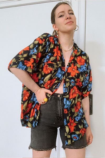 trendy bermuda denim short outfit idea with style blogger gabrielle arruda wearing agolde denim short with men's hawaiian shirt , double hoop earrings and winged eyeliner