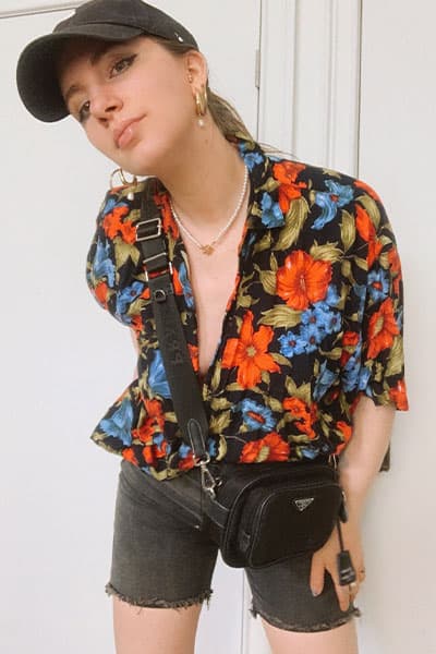 trendy long denim short outfit with hawaiian shirt, agold black denim short, nike baseball hat, and pearl necklace and prada re-edition bag