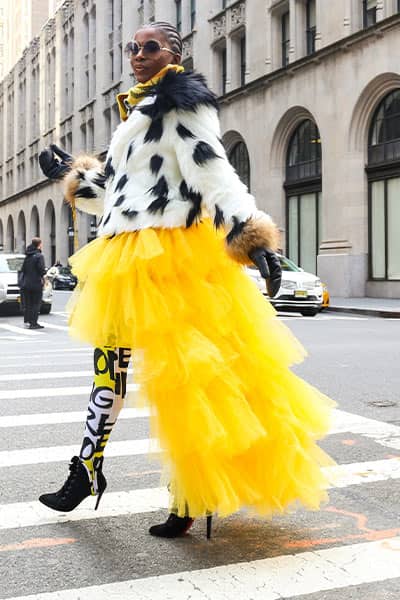 woman wearing yellow tutu dress with printed tights and spotted fur coat, fashion mistake: wearing too much color and print without strategy and know how 