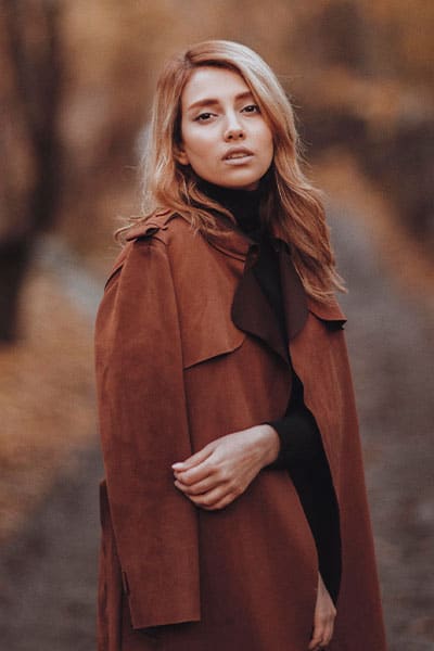 woman in brown trench coat with silk scarf, timeless style example