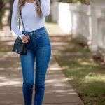 woman wearing fitted long sleeve shirt with high rise slim jeans with heels, crossbody jeans, and sunglasses