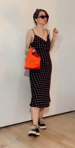 style blogger gabrielle arruda wearing midi silk polka dot dress with tennis shoes, sunglasses, and prada nylon handbag for first date outfit idea casual 