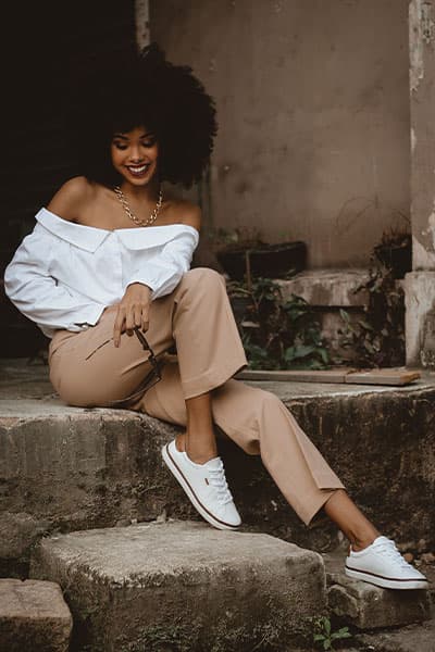 woman wearing off the shoulder blouse with tan trousers and tennis shoes with gold link necklace, first date outfit idea