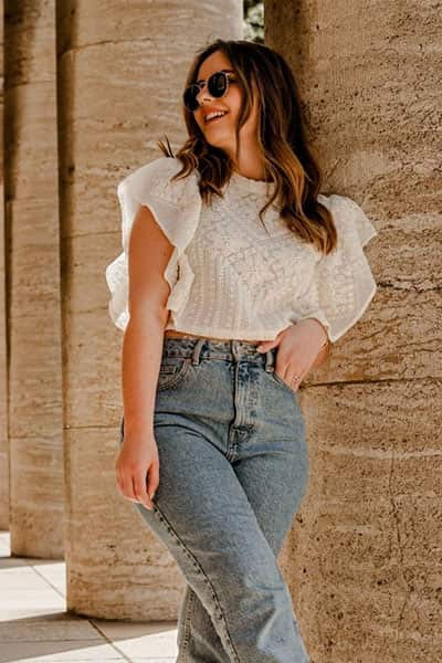 midsize woman in jeans with lacey blosue and flounce sleeves and sunglasses