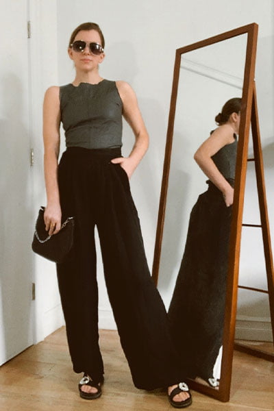 gabrielle arruda in a rosie huntington whiteley outfit idea: black leather boatneck top with wide leg silk trousers and black dad sandsl. black clutch and sunglasses
