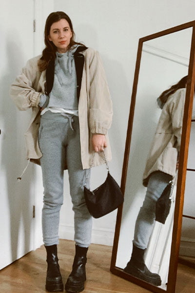 style blogger gabrielle arruda in a rosie huntington-whiteley outfit inspiration. gray sweatsuit with chunky black boots, and a trench coat over, with black nylon prada bag