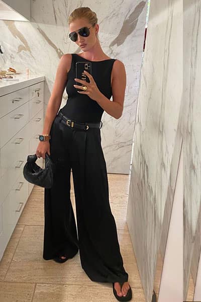 rosie huntington whiteley in black boatneck, wideleg trouser, belt, and flip flop sandals and aviators