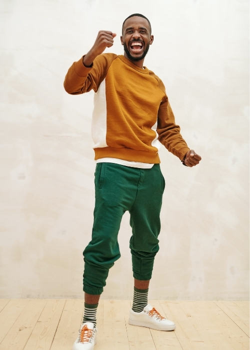 man wearing ochre sweater and forest green joggers to show how to color block