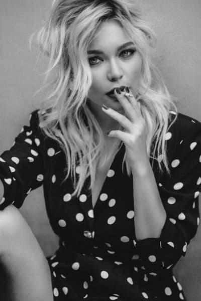 woman with tousled french style hair and black and white polka dot wrap dress smoking a cigarette