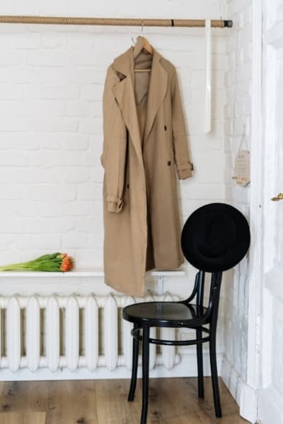 classic french trench coat hanging in closet 