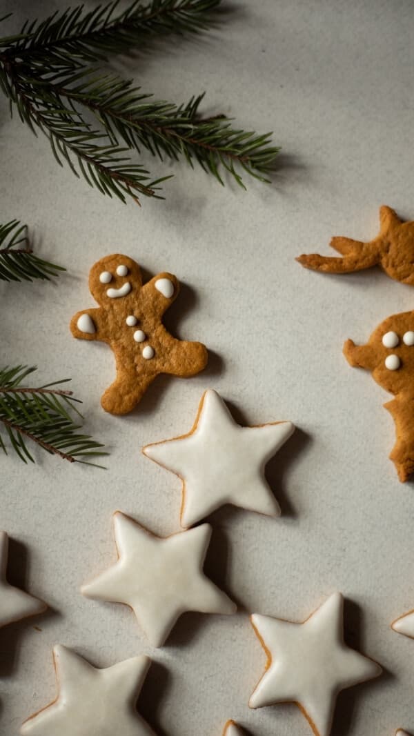 simple holiday wallpaper background, gingerbread cookies (star shaped) with icing and a gingerbread cookie man at top with sprigs of evergreen on side 