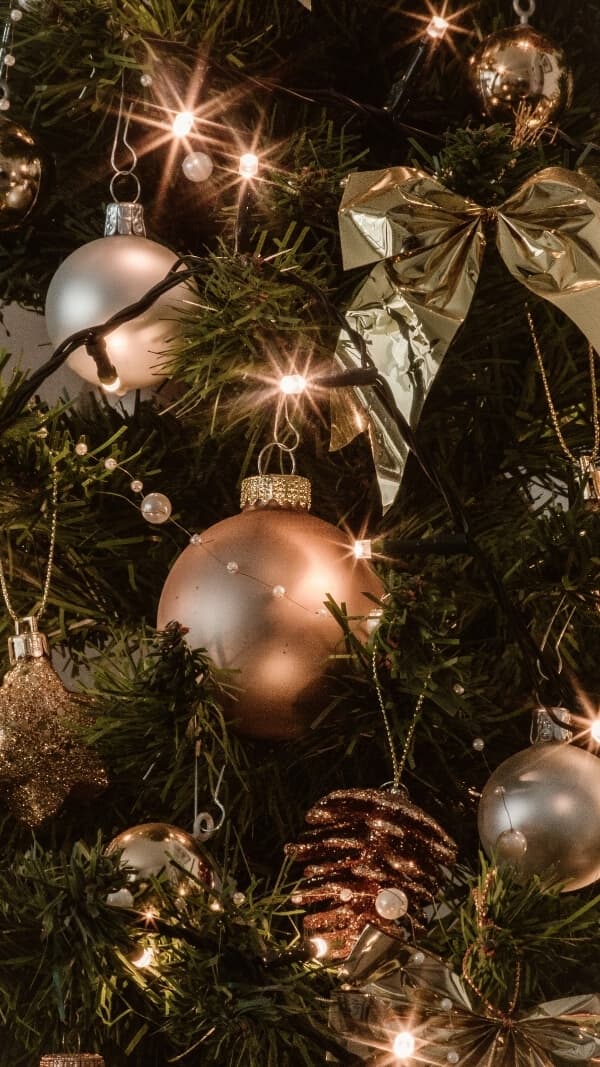 darker close up image of gold ornaments and pinecones on christmas tree- simple christmas background for phone