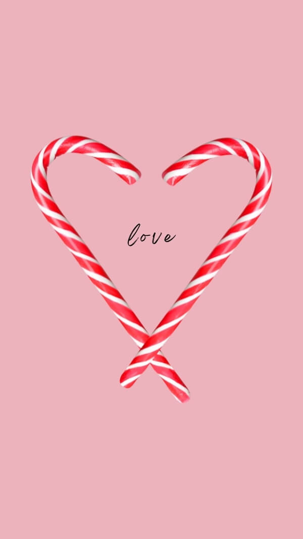 pink background with two candy canes making the shape of a heart and the word "love" in script font in center. holiday wallpaper background