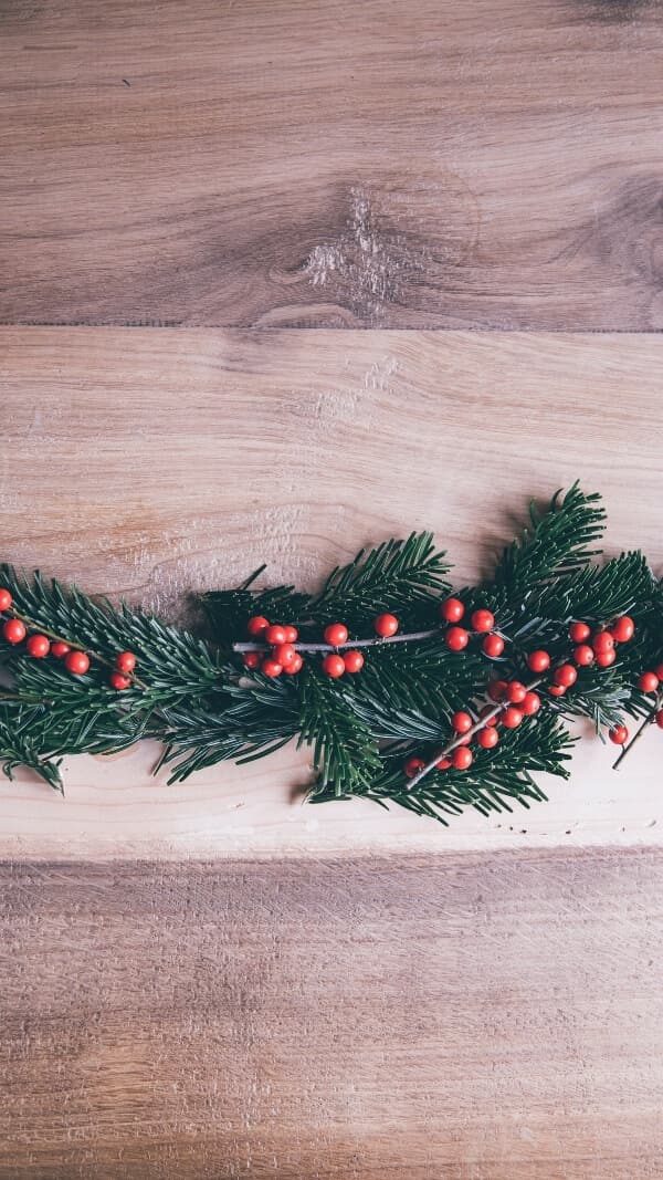 wood grain with evergreen sprigs and mistletoe across the middle. natural, simple holiday wallpaper background