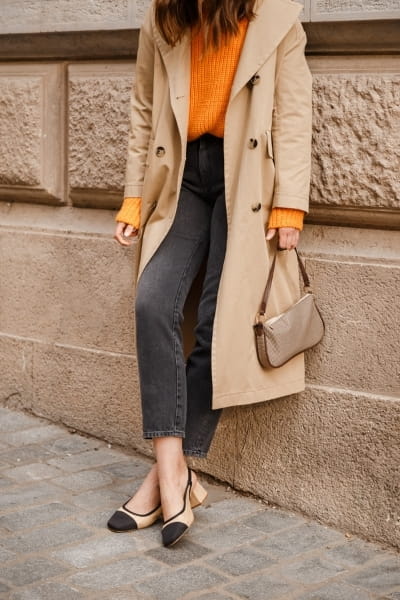 woman in large lapel coat with french-tucked chunk orange sweater and cropped black/gray jeans, outfit idea for rectangle body shape 