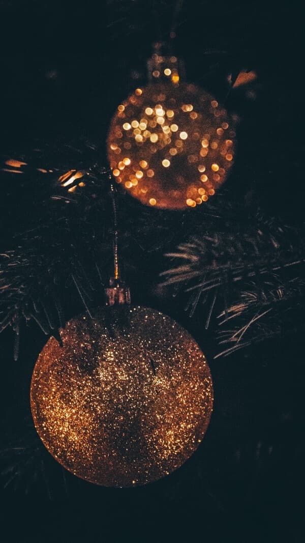 dark background with two gold, sparkly ornaments, Christmas wallpaper for phone