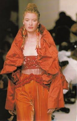 Romeo gigfl runway show model, wearing ethereal outfit to show the angelic essence: draped puffy cape with beaded top and satin trousers with long ornate earrings 