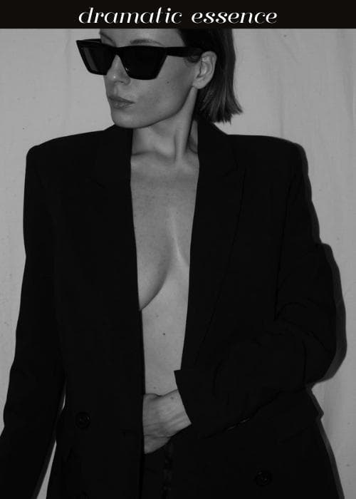 woman with sharp sunglasses and black suit jacket with nothing underneath to show dramatic style essence
