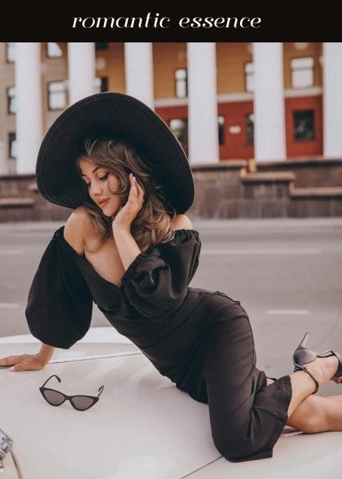 girl in body hugging black dress that's off the shoulder with romantic hair and large hat to show romantic style essence vibes