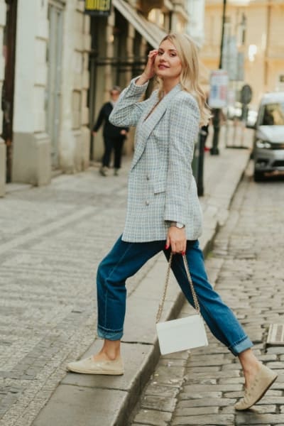 woman wearing tweed blazer with straight blue jeans and loafers in classic style