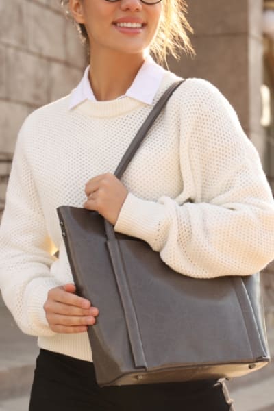 woman in classic preppy outfit holding a leather tote 