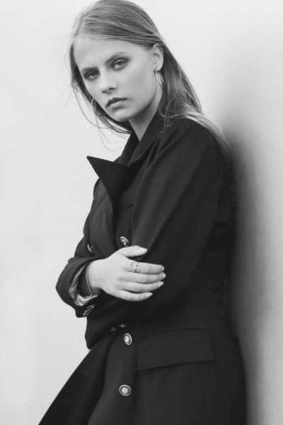 black and white photo of woman in classic trench coat black with gold buttons