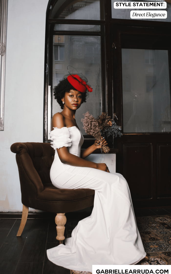 style statement example "Josie" : beautiful woman in white polished dress with red vintage hat and flowers in hand